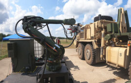 一个机器人手臂在一辆军用车辆旁边拿着一根加油软管